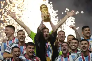 ionel Messi lifting the FIFA World Cup trophy with the Argentina national team, celebrating their victory amidst fireworks.