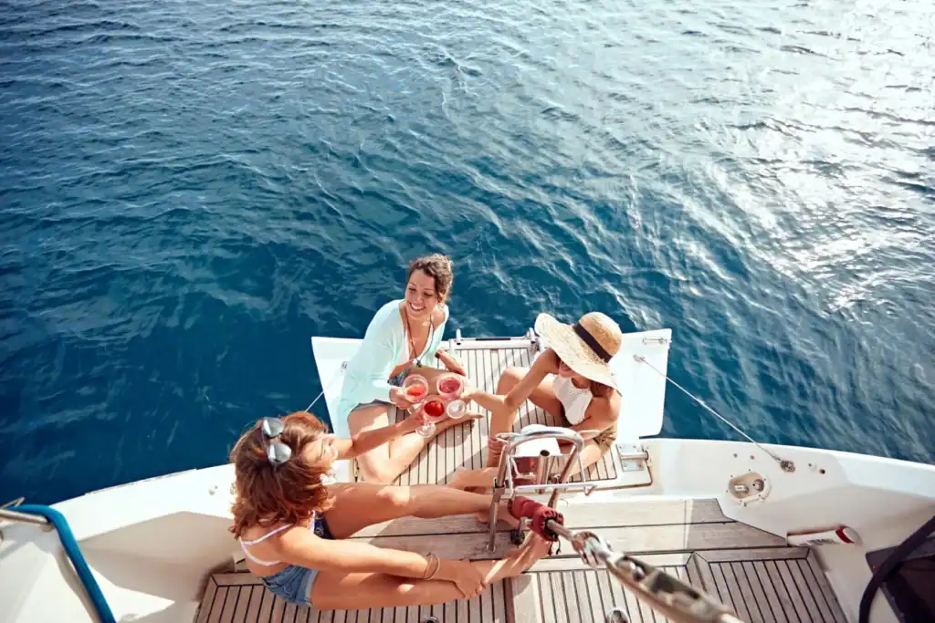 Three women relaxing on a yacht deck while cruising through turquoise tropical waters in Thailand.
