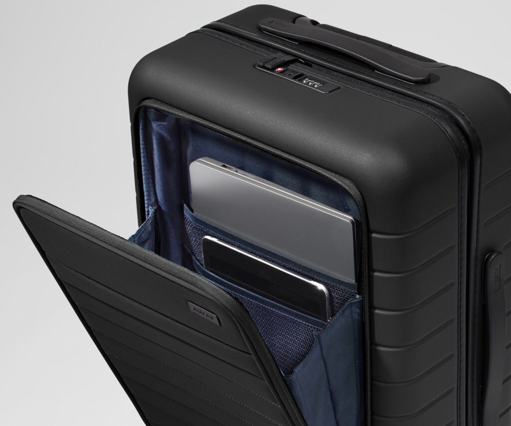 Side profile of a premium matte black hard-shell suitcase standing upright on wheels against a clean white background.