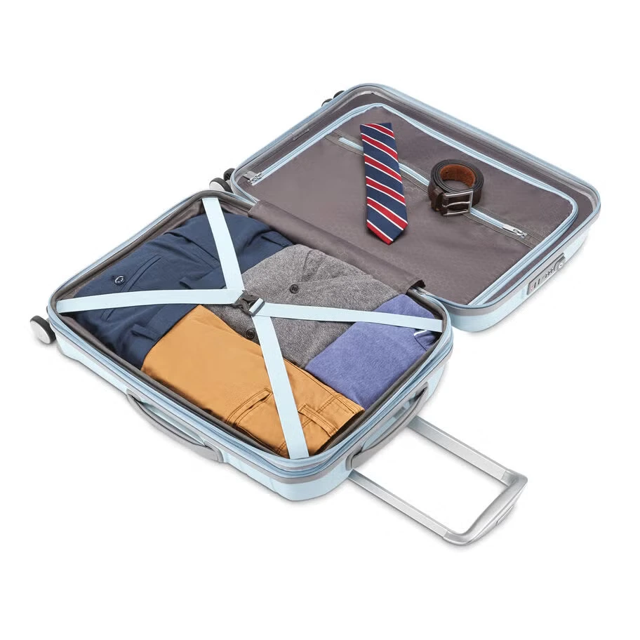 A close-up view of a light blue suitcase, highlighting its extendable metallic handle, top carry handle, and integrated combination lock.