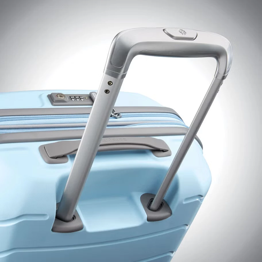 A close-up view of a light blue suitcase, highlighting its extendable metallic handle, top carry handle, and integrated combination lock.