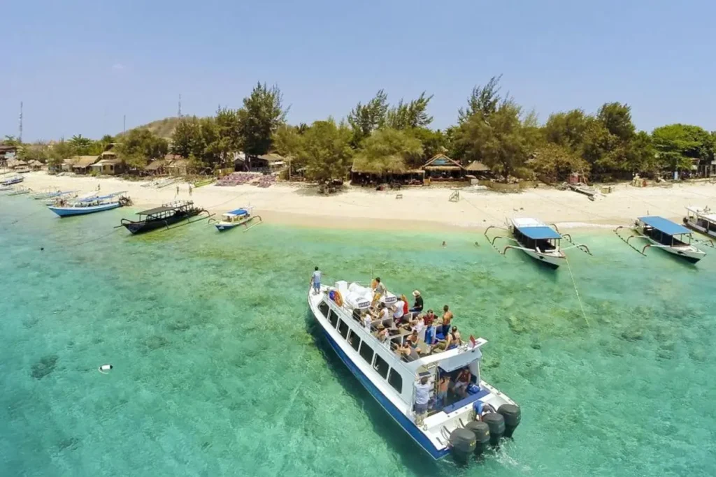 A beautiful high-angle view of the lush green Perhentian Islands surrounded by crystal-clear turquoise waters and a sandy beach under a partly cloudy sky.