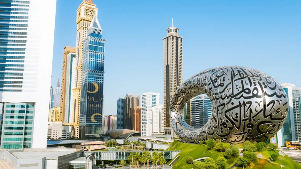 The iconic, ring-shaped Museum of the Future in Dubai, featuring intricate Arabic calligraphy, surrounded by modern skyscrapers and greenery.