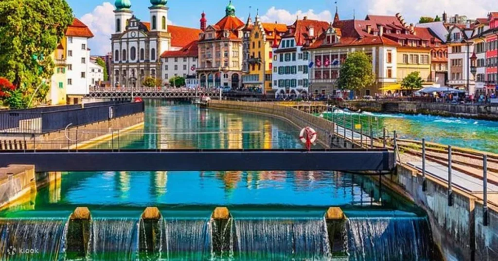 A beautiful view of the iconic Chapel Bridge in Lucerne, Switzerland, with the historic water tower and surrounding mountains in the background