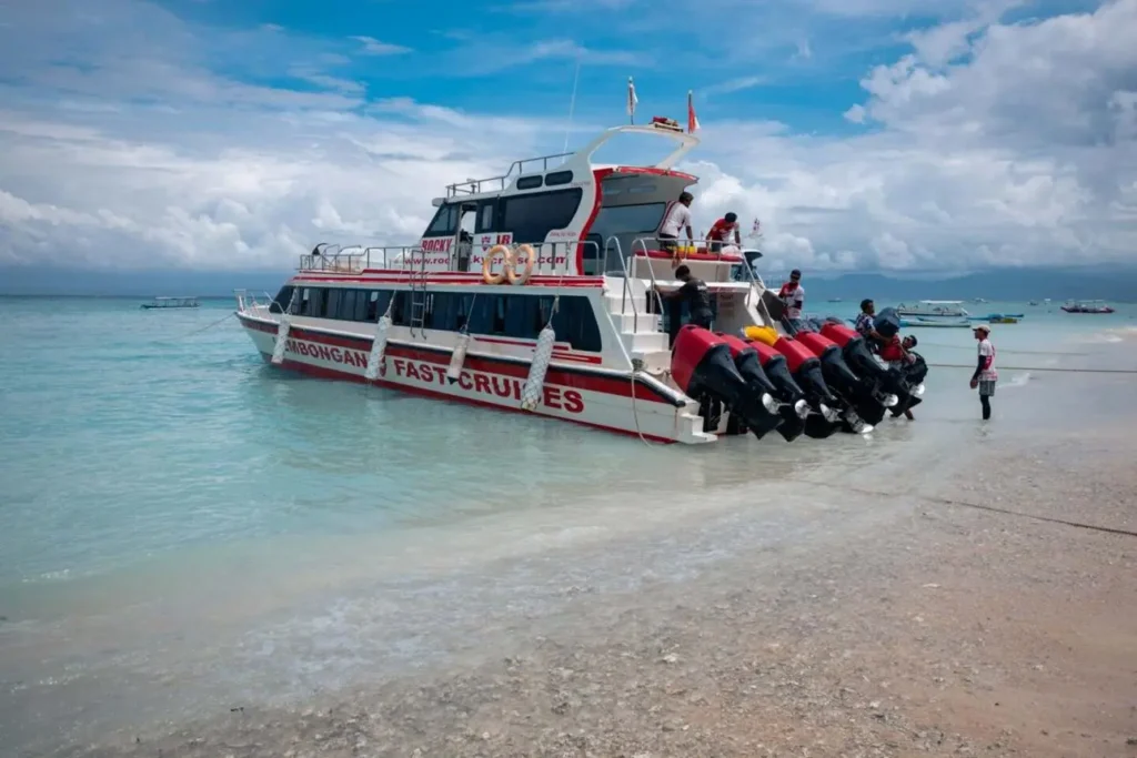 An aerial view of the white Arthamas Express speedboat cruising at high speed over clear, turquoise, shallow coral reef waters.