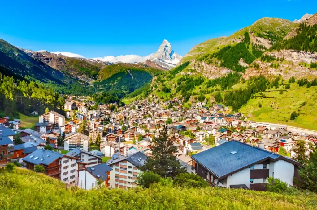 The car-free village of Zermatt in Switzerland with classic wooden chalets and the majestic, snow-covered Matterhorn mountain behind.