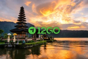 A beautiful sunset view of the iconic Pura Ulun Danu Bratan temple on the water in Bali, featuring the 12GO logo centered against a dramatic golden sky.