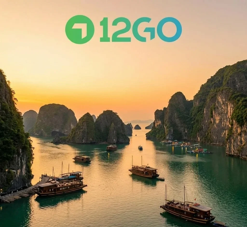 A high-angle view of traditional wooden junk boats cruising through the calm emerald waters of Halong Bay surrounded by dramatic limestone karst islands at sunset.