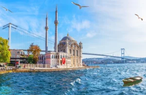 The beautiful Ortaköy Mosque situated on the water's edge in Istanbul, with the Bosphorus Bridge and seagulls in the background.