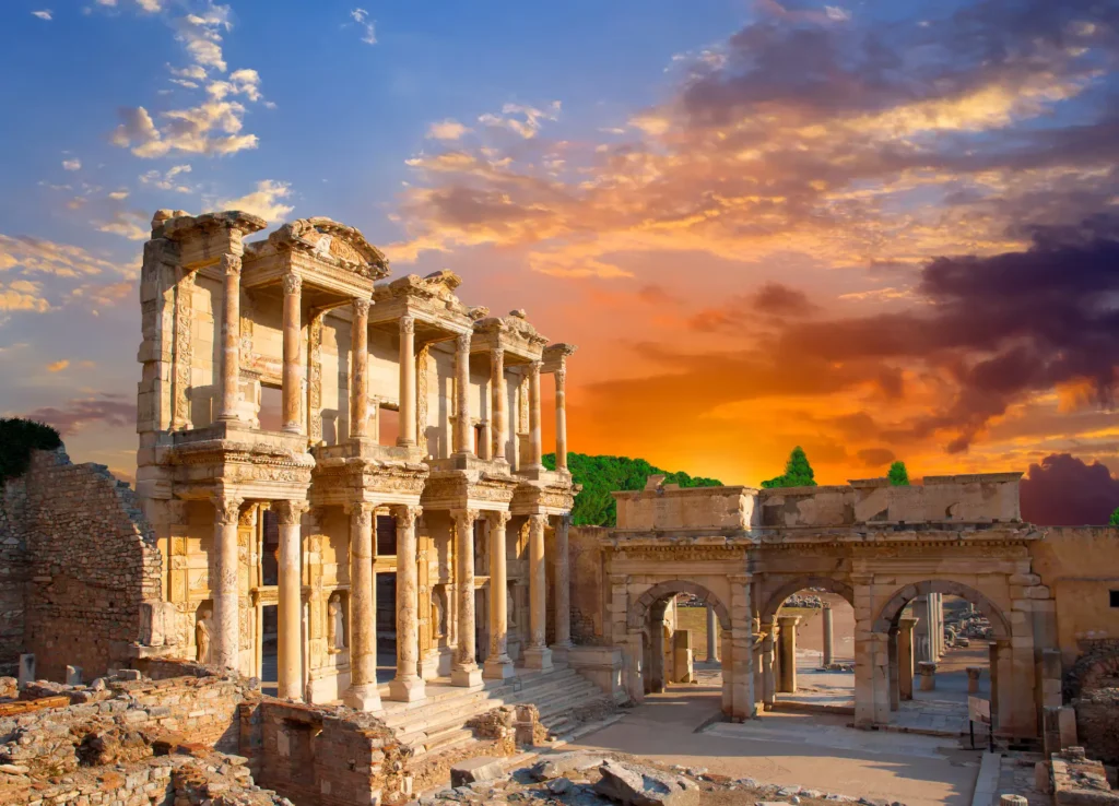 The magnificent Library of Celsus in Ephesus, Turkey, bathed in the warm, vibrant colors of a dramatic sunset sky.