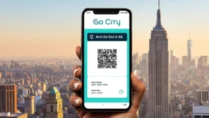 A hand holding a smartphone displaying a Go City digital pass featuring a QR code, order number, and expiry date against a New York City skyline.