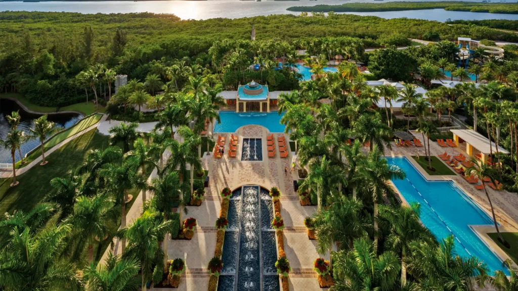 Aerial view of Hyatt Regency Coconut Point Resort and Spa featuring expansive swimming pools, fountains, palm trees, and lush surrounding grounds