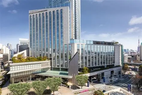 Exterior view of the Grand Hyatt Tokyo hotel building with modern glass architecture, street traffic, and trees in the foreground.