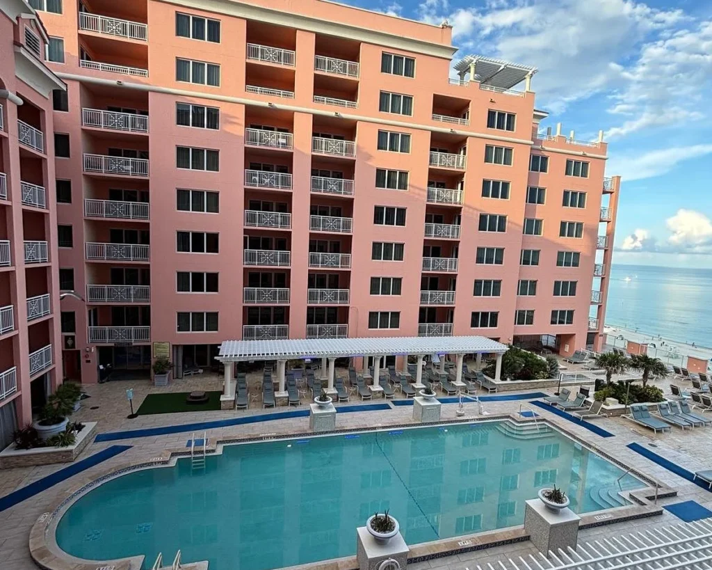 High-angle balcony view of Hyatt Regency Clearwater Beach Resort showing its outdoor swimming pool, deck area, and Gulf of Mexico views.