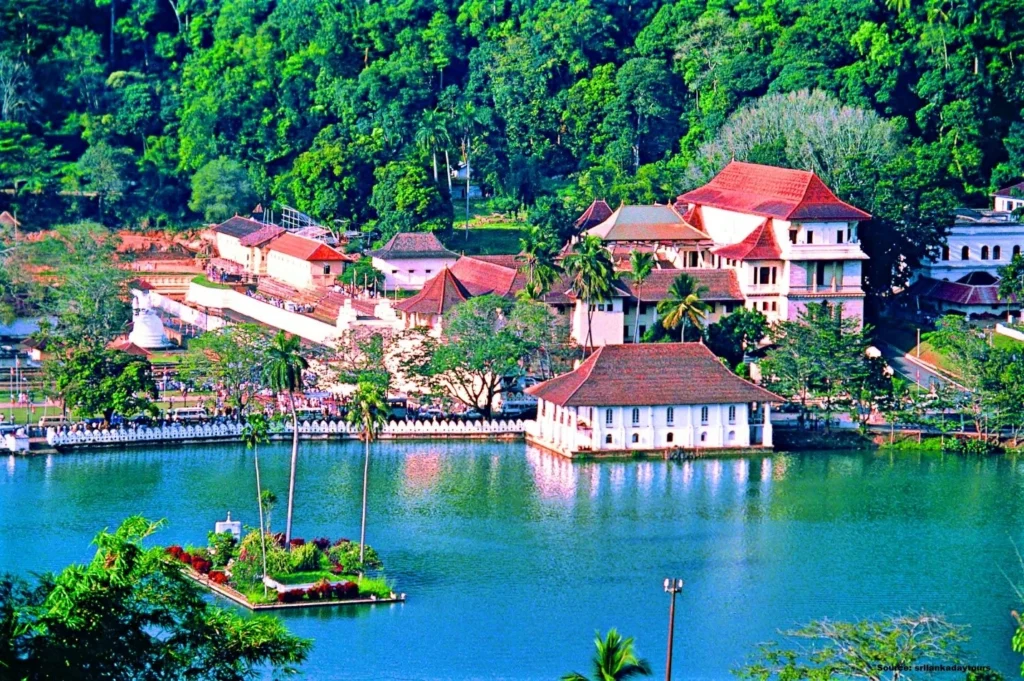 Elevated view of the Temple of the Sacred Tooth Relic situated by a scenic lake surrounded by lush green trees in Kandy, Sri Lanka
