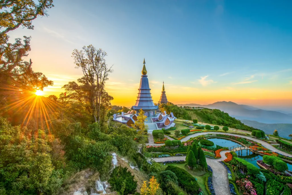 Scenic view of the Napamaytanidol Chedi pagoda surrounded by landscaped gardens and mountains at sunrise in Doi Inthanon National Park, Thailand.