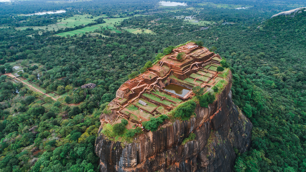 Aerial view of the ancient Sigiriya Rock Fortress surrounded by lush green forests and gardens in Sri Lanka