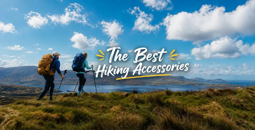 Two hikers with backpacks and trekking poles walking along a grassy ridge overlooking a lake and distant mountain ranges