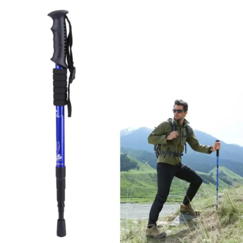 Close-up of a blue telescopic trekking pole alongside a hiker trekking uphill in a scenic mountain landscape