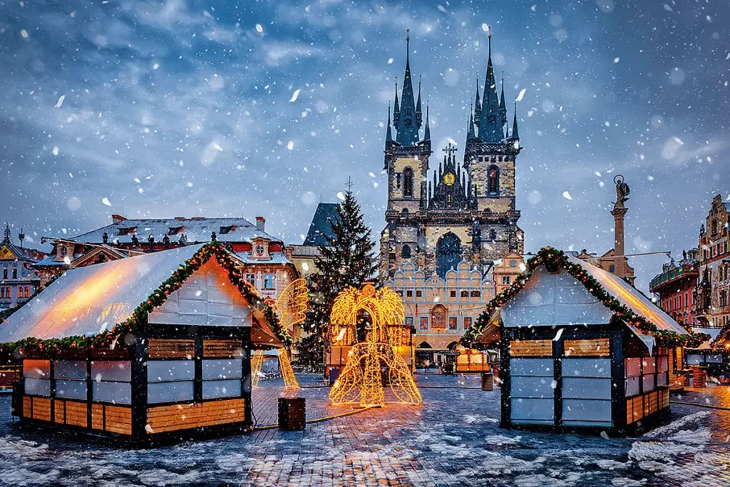 A magical snowy evening at the Prague Christmas market in front of the historic Tyn Church.